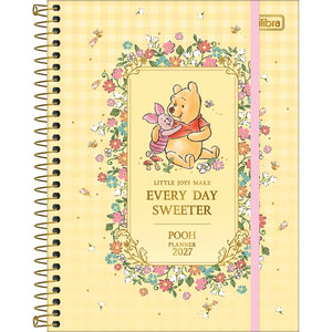 Capa do Planner Espiral Grande Ursinho Pooh 2027 da Tilibra, em tom amarelo xadrez, com ilustração de Pooh e Leitão abraçados emoldurados por flores, detalhe metalizado dourado e elástico rosa.